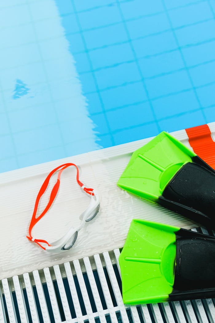 Green flippers and goggles placed poolside ready for swimming activities.